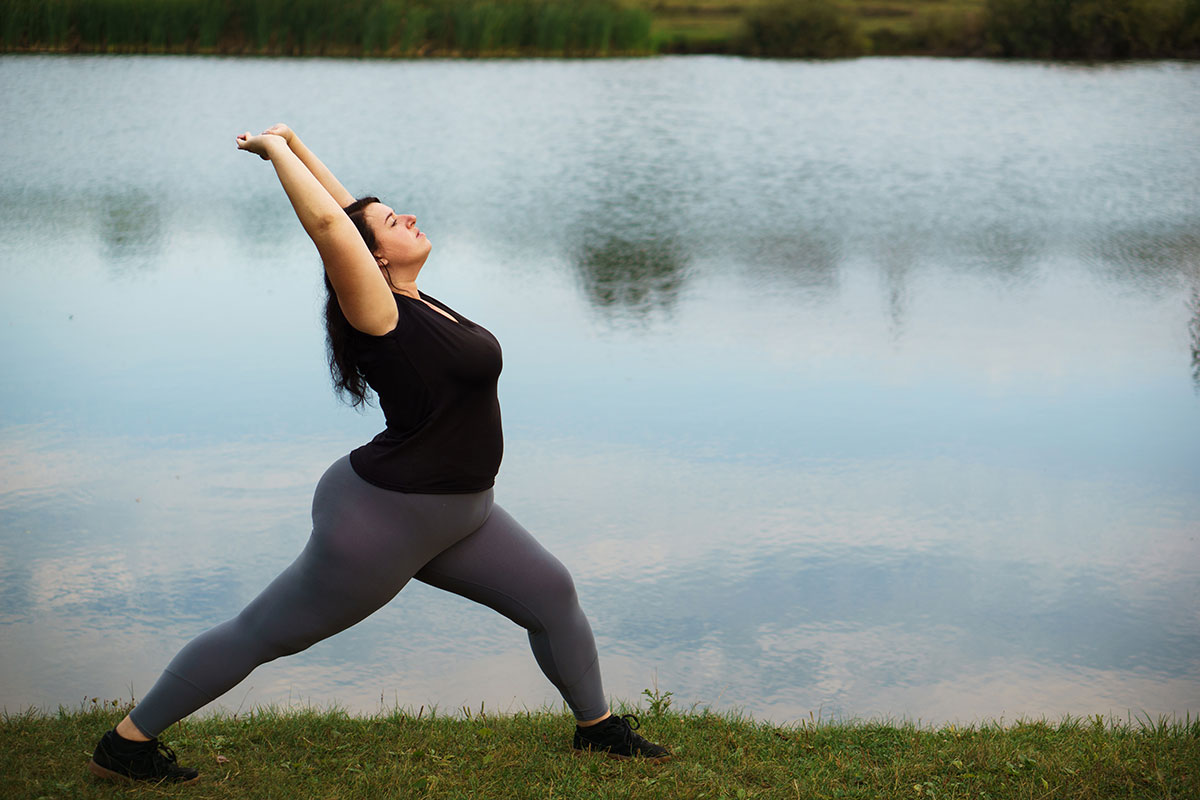 Woman stretching at lake as part of her bariatric surgery recovery