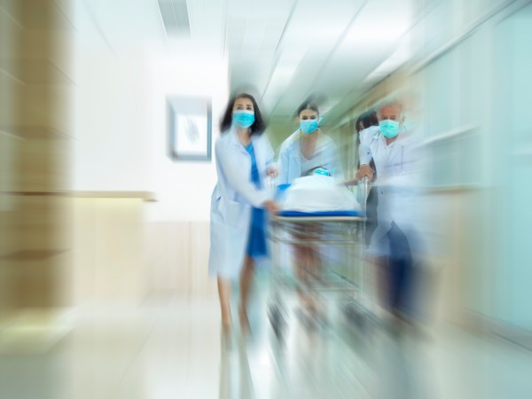 Providers rushing a patient in a hospital bed down a hallway 