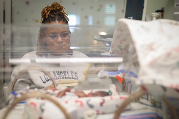 A baby in a NICU bed with the mother nearby