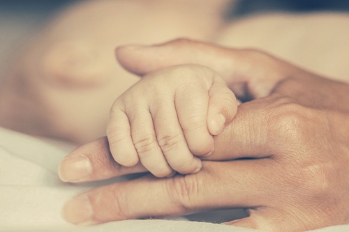 Mother's hand holding infant's hand
