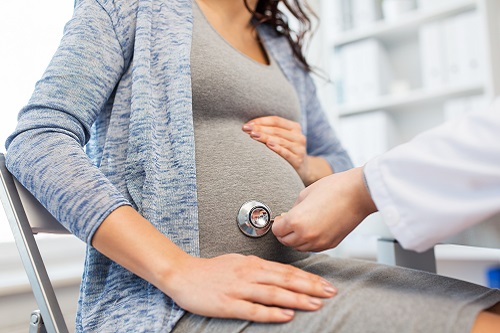 Doctor suing a stethoscope to examine a pregnant woman