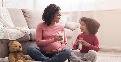 Pregnant woman sitting on living room floor with your daughter