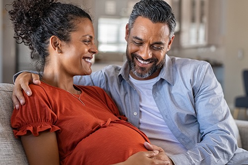 Pregnant woman and husband sitting on couch