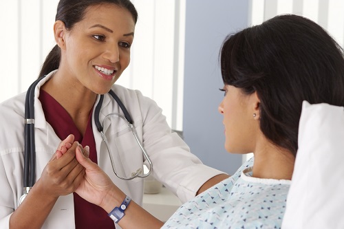 Woman in hospital bed speaking with physician