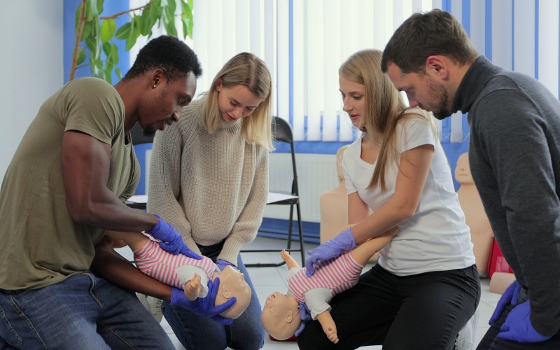 People watching an assisted breathing demonstration on a baby mannequin