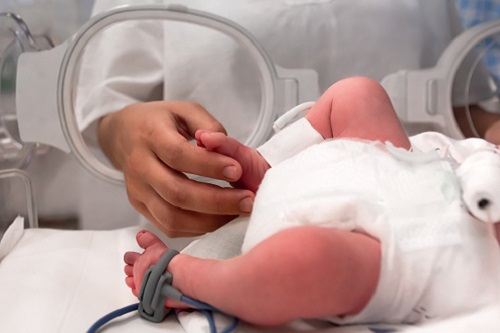 parent holding baby's foot in NICU