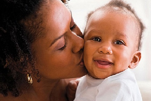 Mother holding and kissing infant baby