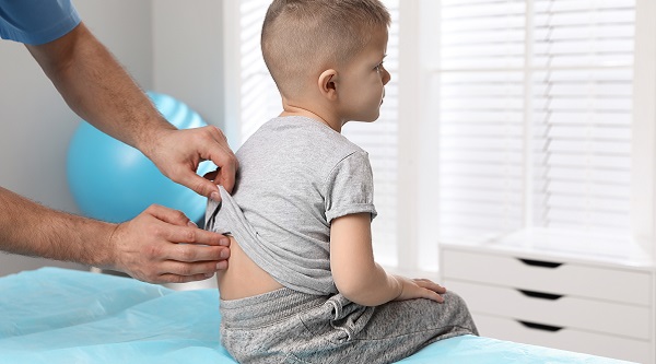 child having his spine examined by doctor