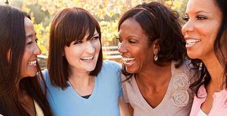 Four women stand together laughing