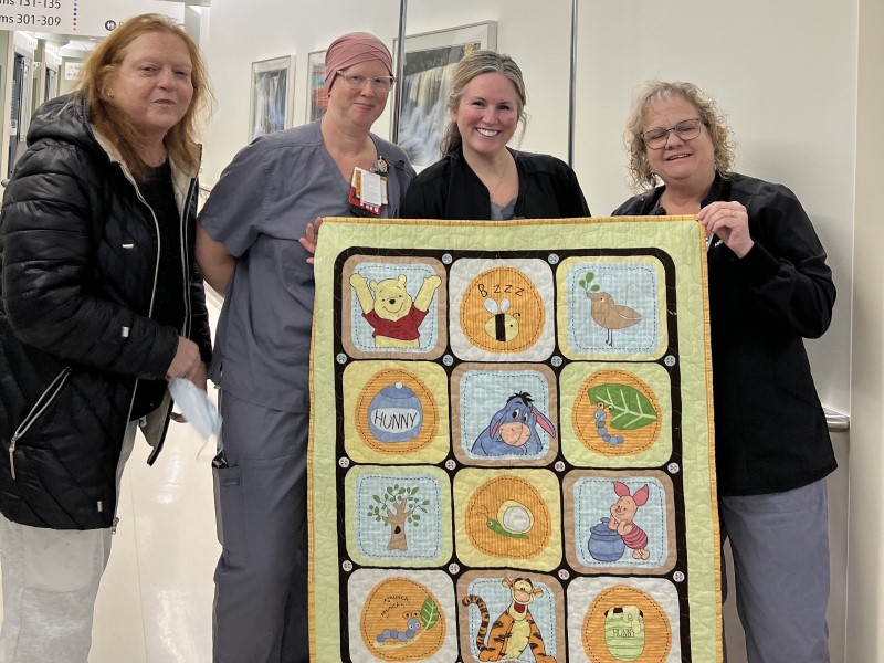 Volunteers and nurses holding a quilt