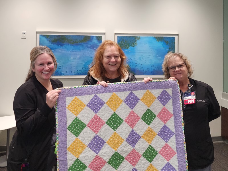 Volunteers and nurses holding a quilt