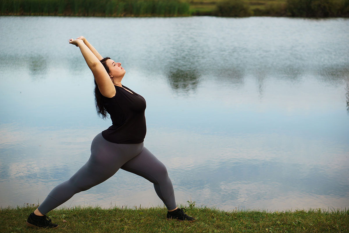 Woman stretching at lake as part of her bariatric surgery recovery