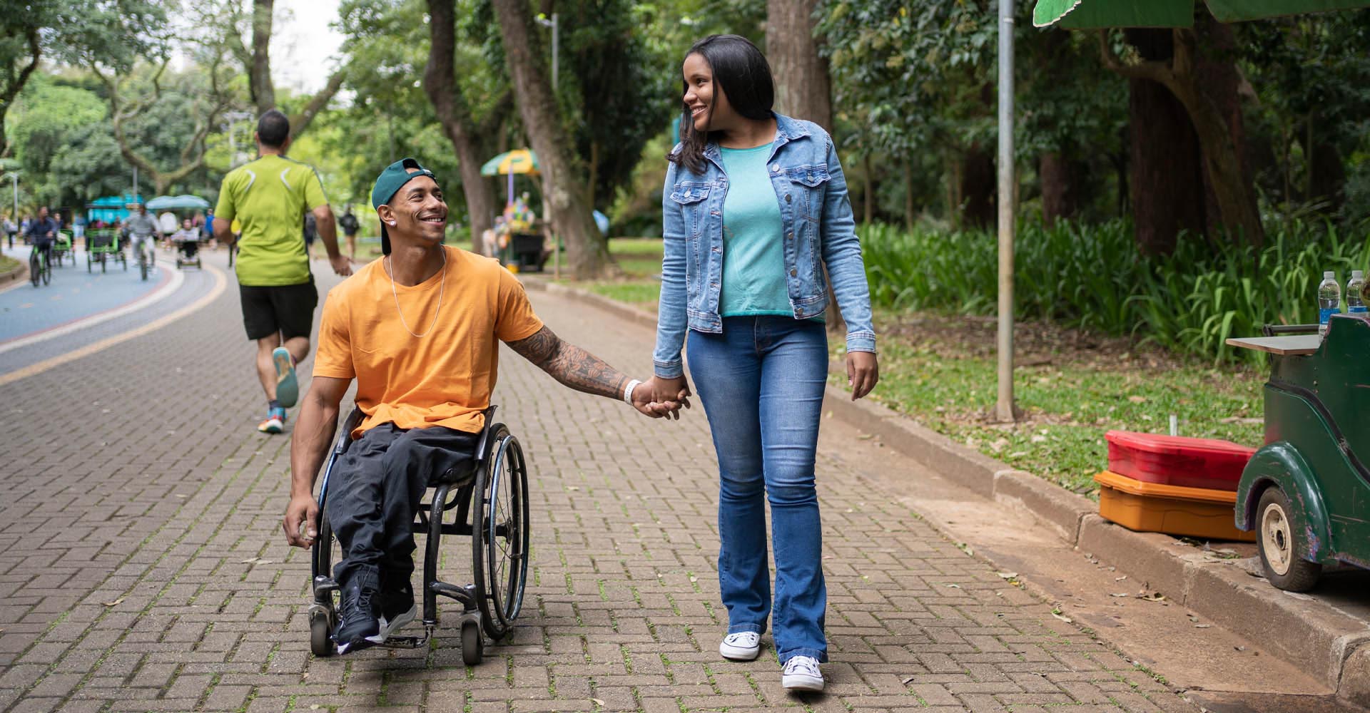 Woman walking and holding hands with a man in a wheelchair