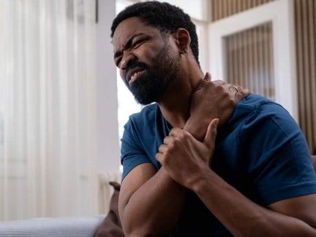 A man feeling intense pain in his upper shoulder