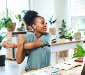 A woman performing stretches at her desk