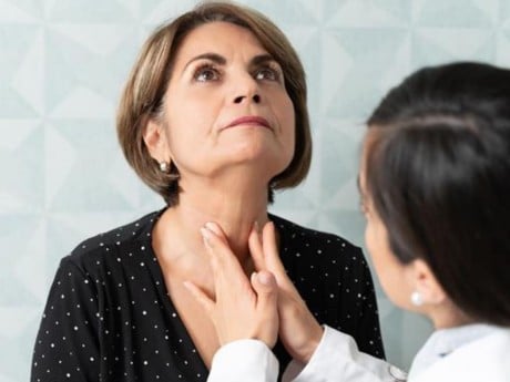 A doctor performing a thyroid exam on a patient