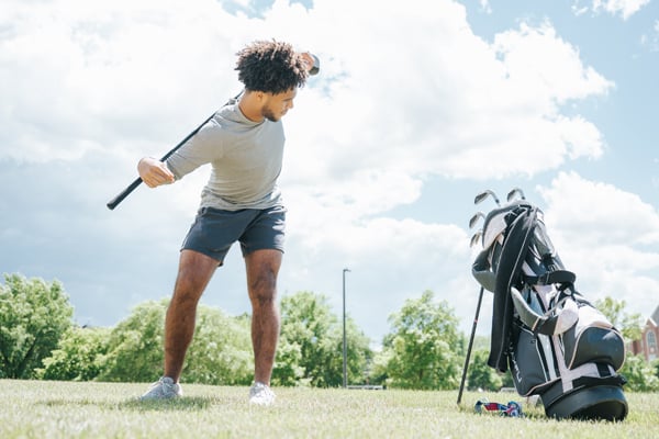 A golf player stretching using a club