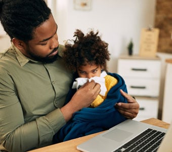 A father holding his child who has a runny nose