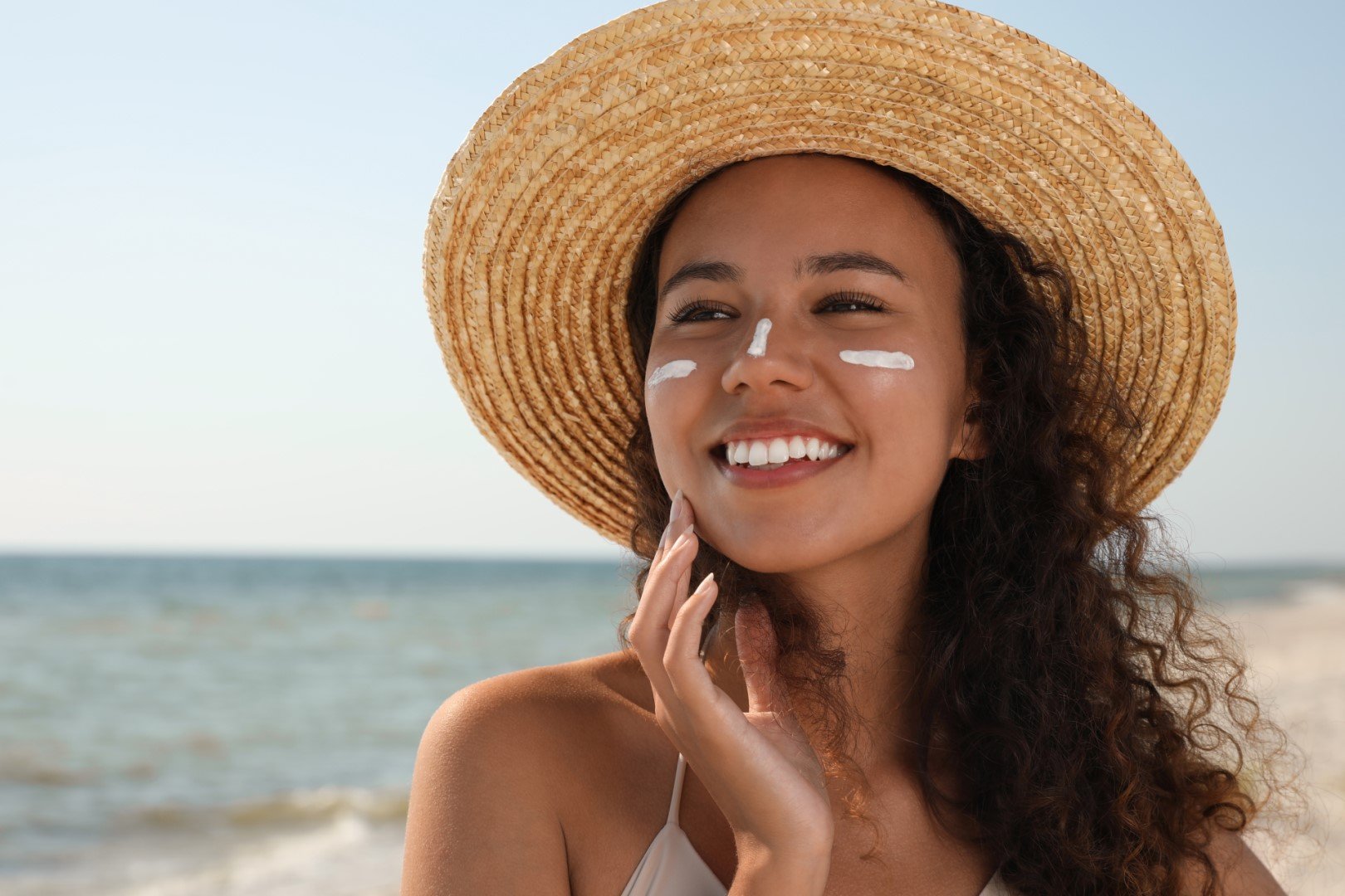 Woman in hat with sunscreen on face