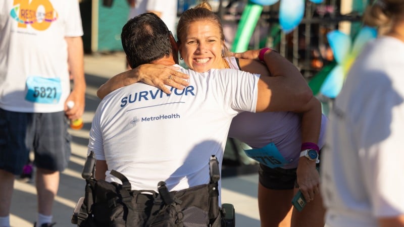 A trauma survivor in a wheelchair hugging a woman