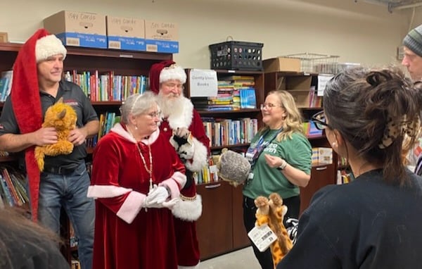 Matt "Ogre" Whaley, Santa Claus, and Mrs. Claus holding stuffed animals and talking to MetroHealth staff