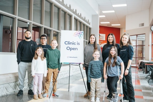 Students standing next to a School Health Program clinic sign
