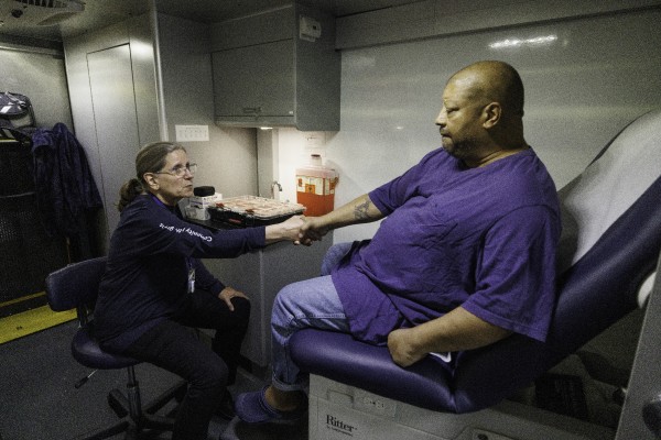 A patient shaking hands with Bridget Gill inside the mobile unit