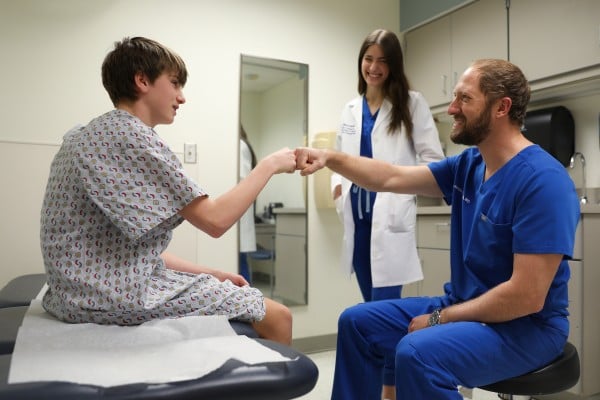 A young patient and his pediatric orthopedic team in an exam room