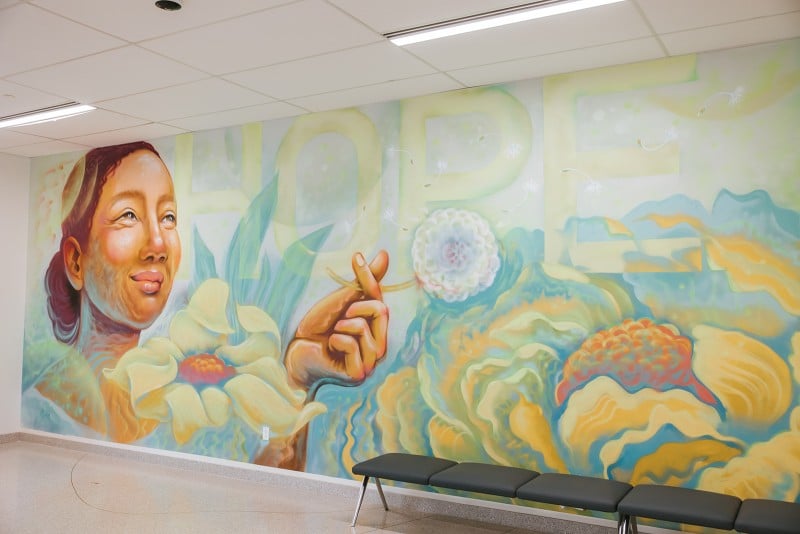 A mural including a woman holding a dandelion with the word HOPE in the background