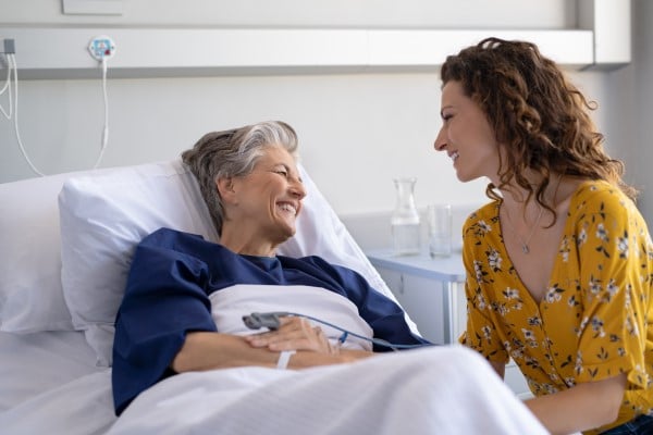 A daughter visiting her mother in a hospital room