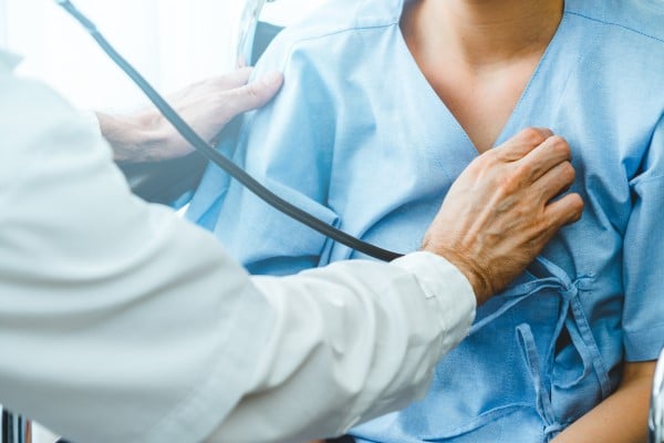 A doctor takes a patient's pulse with a stethoscope