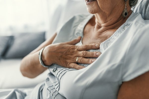 A woman holding her hand to her chest in pain