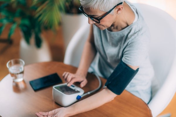 Woman with blood pressure monitor and phone