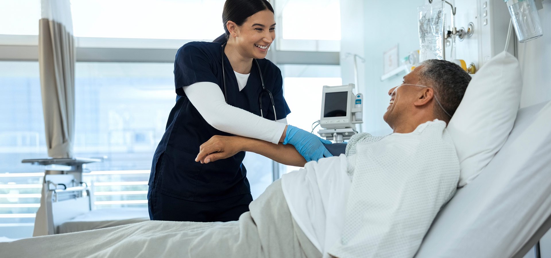 A provider checks on a patient recovering in a hospital bed