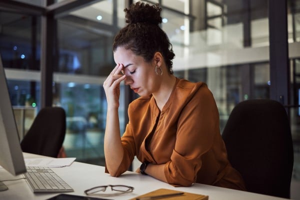 A woman at her desk feeling exhausted