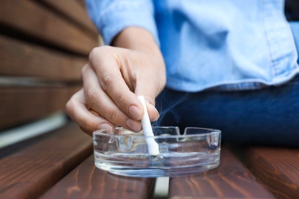 A person putting out a cigarette in an ashtray