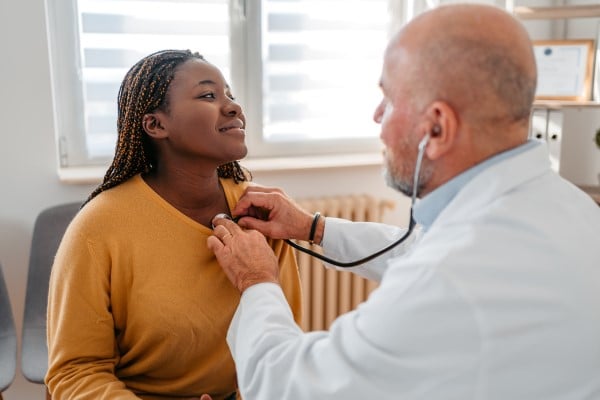 A doctor listening to a woman's heart with a stethoscope