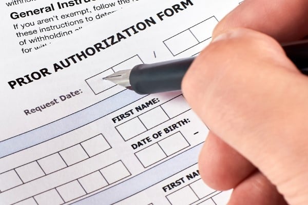 hand filling our Prior Authorization Form