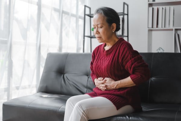 Woman grimacing while holding stomach