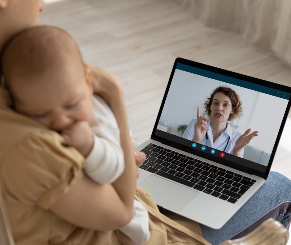 Parent holding baby on video visit with doctor