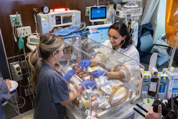 Nurse and mom looking at baby in bed