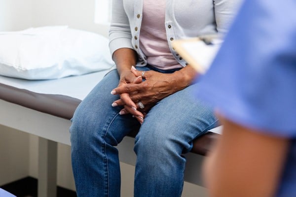 woman sitting on exam table with hands folded