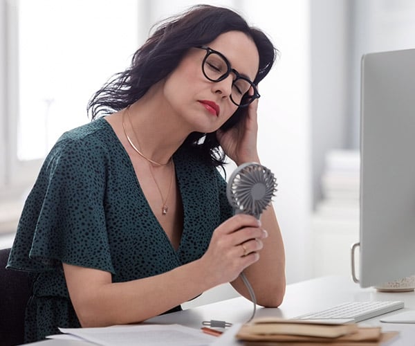 A woman holding a personal fan to cool off