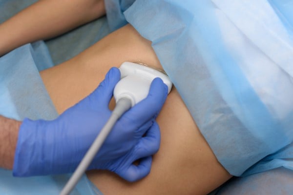 Ultrasound wand on female's stomach