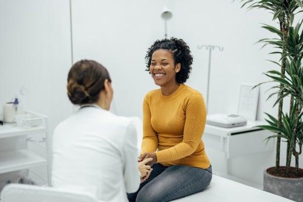 woman sitting on exam table smiling at provider