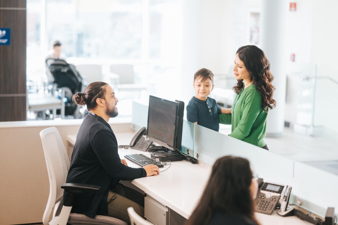 A mother and child at a reception desk in the Outpatient Health Center