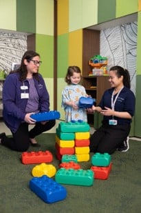 A child patient playing with blocks along with Child Life Specialists