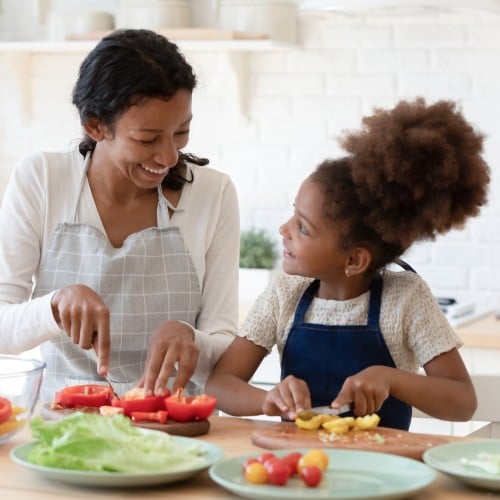 A child preparing vegetables with her mother