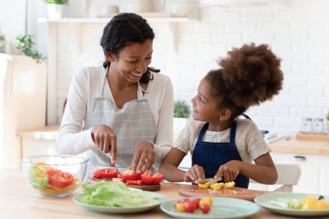 A child preparing vegetables with her mother