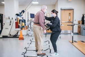 An elderly patient standing upright with help